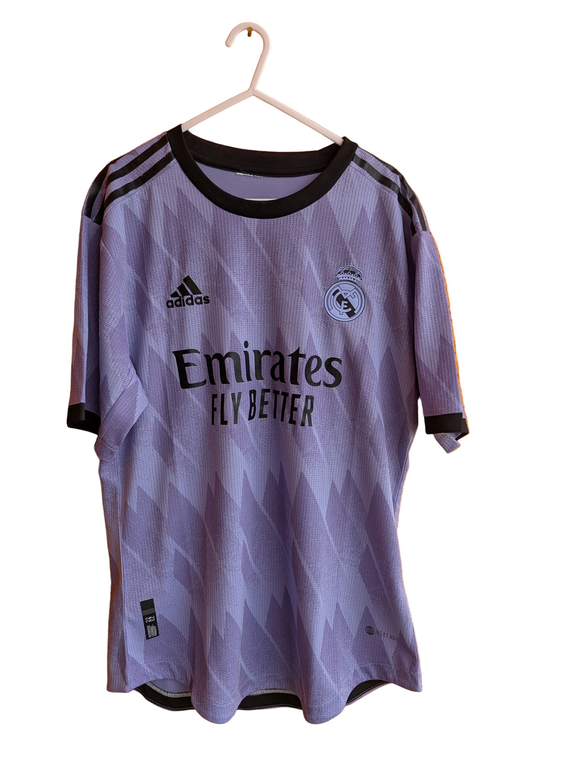 Purple sports jersey with black accents on a hanger against an orange wall